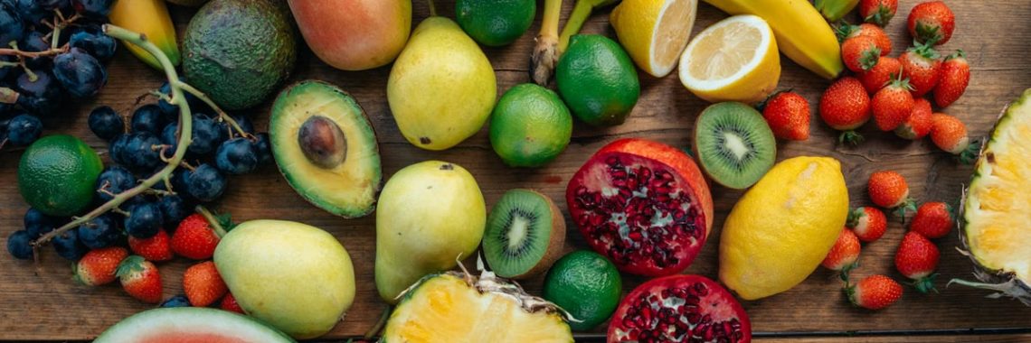 Colorful variety of fresh fruits including watermelon, pineapple, and grapes on a wooden surface.